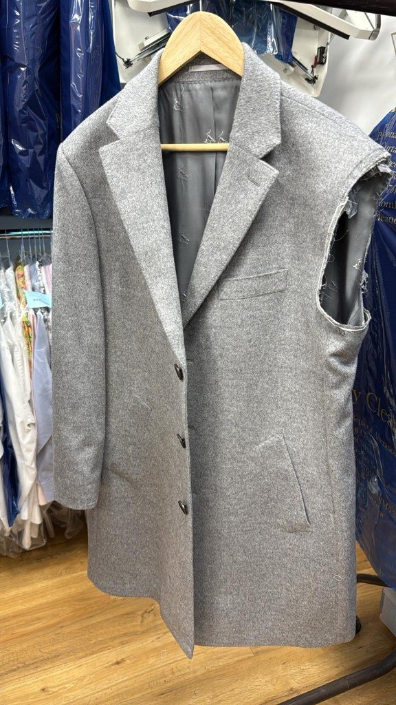 Grey overcoat on the rail in our Collier Row shop with one sleeve taken off at the shoulder